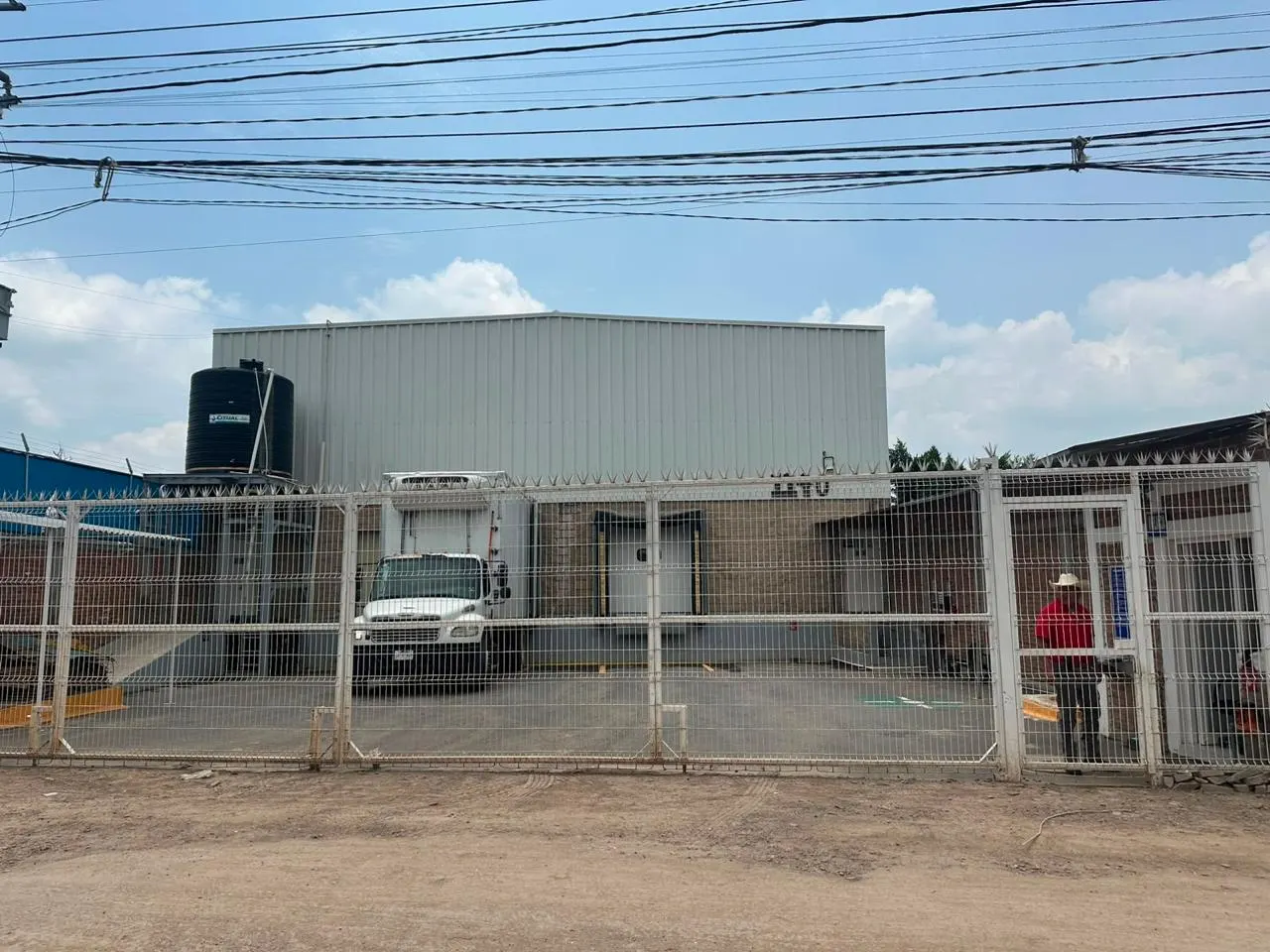 Acceso controlado a las instalaciones de Puente Viejo con la nave industrial al fondo.